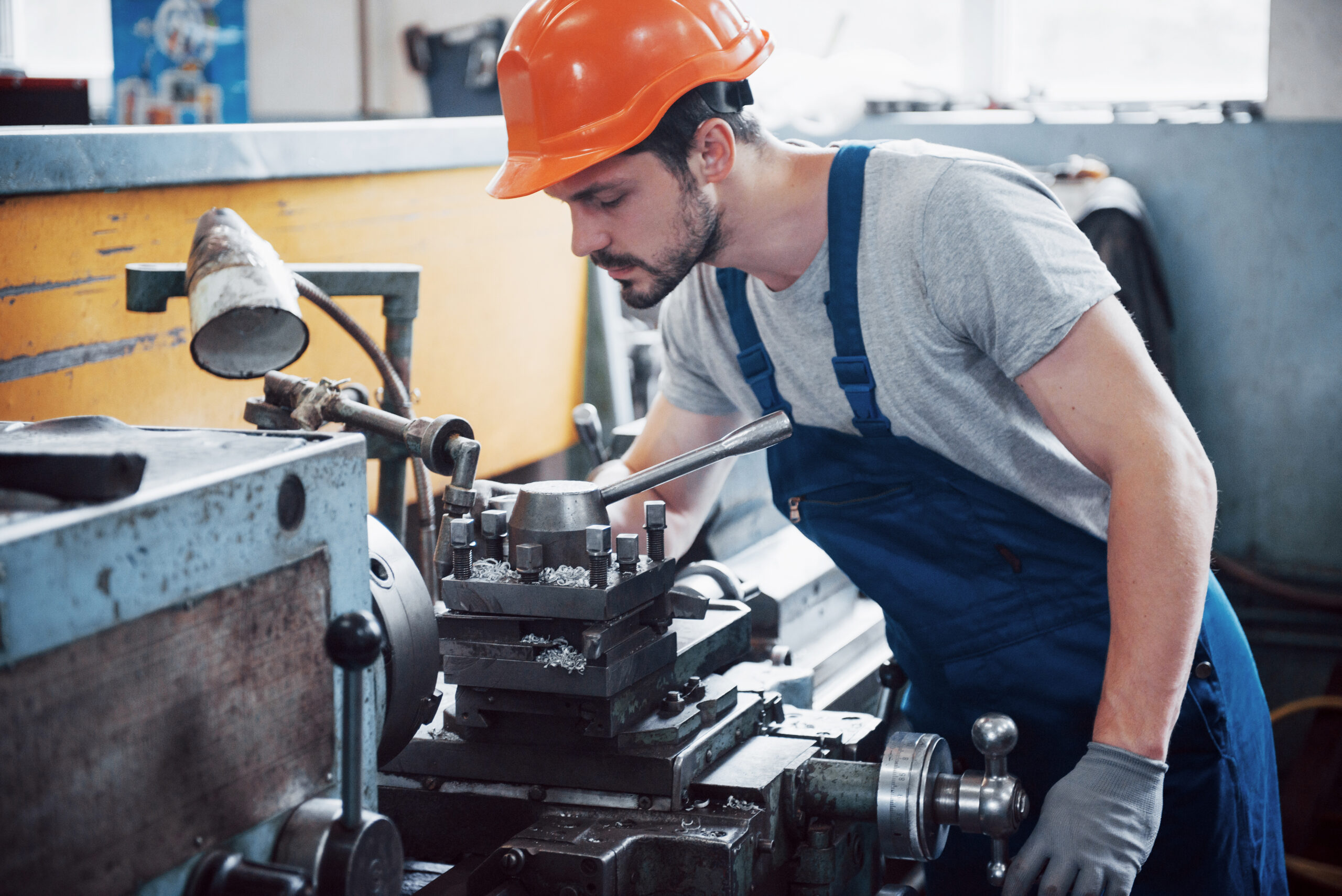 Portrait of a young worker in a hard hat at a large waste recycling factory. The engineer monitors the work of machines and other equipment Portrait of a young worker in a hard hat at a large waste recycling factory. The engineer monitors the work of machines and other equipment.